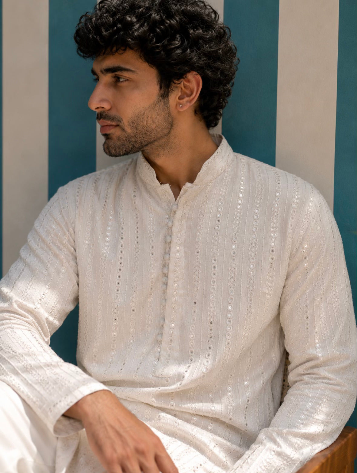 Man wearing AAINA ivory mirror work kurta - seated close view