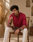 Man wearing hot pink GULAAL kurta, seated holding a rose