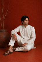Man sitting wearing SUKOON ivory embroidered kurta set - styled shot